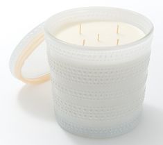 a white candle sitting inside of a glass container