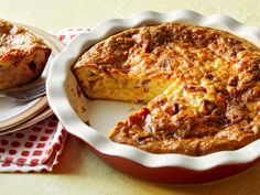 a quiche on a plate with a piece missing from it and another pie in the background