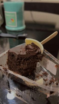 a piece of chocolate cake sitting on top of a plastic container filled with ice cream