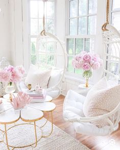 a living room with white furniture and pink flowers in vases on the coffee table