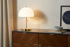 a table with a lamp and some books on it next to a curtained window