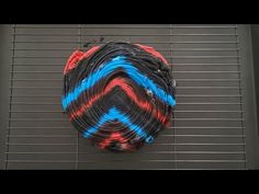 a piece of art that looks like an object with blue, red and black stripes on it