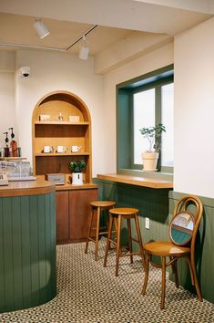 two wooden stools sitting in front of a counter top next to a green wall