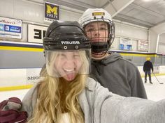 a man and woman taking a selfie in front of an ice hockey goalie