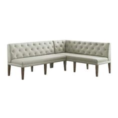 a white sectional couch with wooden legs and tufted upholstered backrests