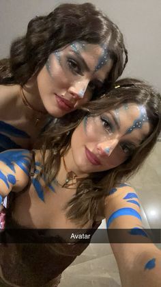 two beautiful young women with painted faces posing for the camera