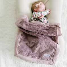 a baby wrapped in a blanket laying on top of a bed