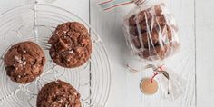 three chocolate cookies on a plate next to a bag of sea salt and peppermint