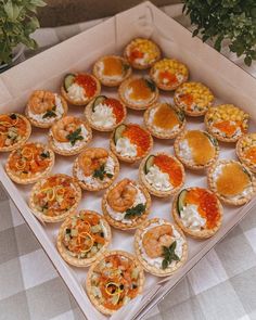 an open box filled with different types of appetizers on top of a table