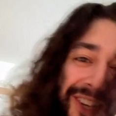 a man with long hair is smiling at the camera