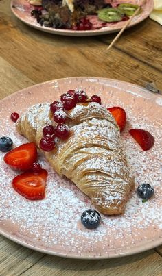 a croissant with berries and powdered sugar on it