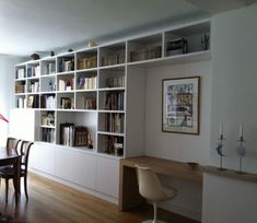 a dining room table and chairs in front of a bookshelf