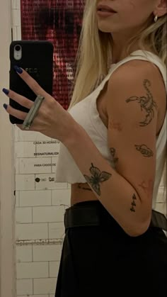 a woman with tattoos on her arm holding a cell phone