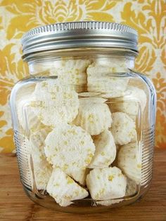 a glass jar filled with white marshmallows on top of a wooden table