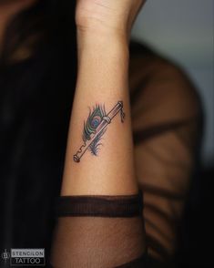 a woman's wrist tattoo with a feather and arrow on the left side of her arm