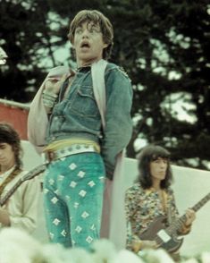 the rolling stones performing on stage in front of a group of young men with guitars