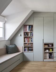 an attic bedroom with built in bookshelves and storage