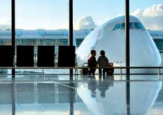 two people are sitting on a bench in front of an airplane at the airport terminal