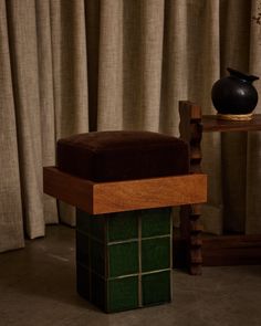 a black vase sitting on top of a wooden table next to a green tiled floor