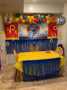 a party table set up with balloons and streamers on the wall for mickey mouse's birthday