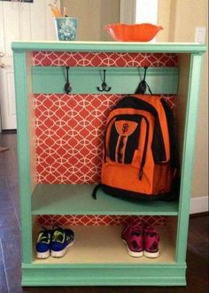 an orange backpack is hanging on a green shelf next to some shoes and a bowl