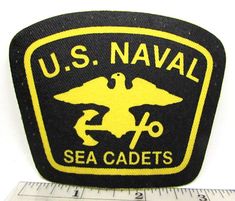 the u s naval sea cadets logo is shown on a black and yellow patch