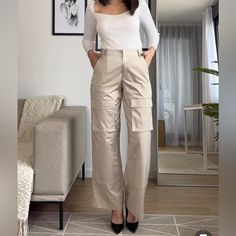 High-Waisted Pants With Side Pockets, False Back Flap Pockets, And Patch Pockets At Legs. Front Zip And Metal Hook Closure. Cargo Style Workwear Trousers, High Waist Wide Leg Cargo Pants For Work, High-waisted Cargo Pants For Work, Beige Ankle-length Cargo Pants For Work, Beige High Waist Non-stretch Cargo Pants, Chic High Waist Cargo Bottoms, Khaki Ankle-length Cargo Pants For Work, High Waist Non-stretch Beige Cargo Pants, Chic Khaki Cargo Pants For Work