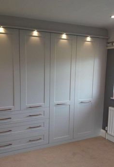 an empty room with white closets and lights on the ceiling, carpeted floor