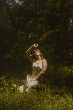 a woman sitting in the grass with her hands on her head