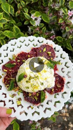 a white plate topped with fruit covered in whipped cream and garnished with green leaves