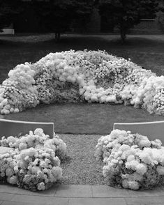 black and white photograph of flowers arranged in the shape of a circle on a park bench