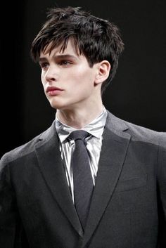 a young man in a suit and tie on the catwalk at a fashion show