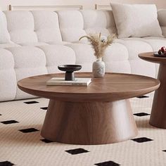 two coffee tables sitting on top of a rug in front of a white sectional couch