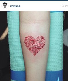 a red heart tattoo on the left forearm and right leg, with an intricate design