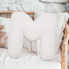 the letter m is made out of white fluffy pillows on a wicker bed frame