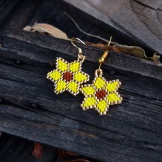 a pair of yellow and brown beaded earrings sitting on top of a piece of wood