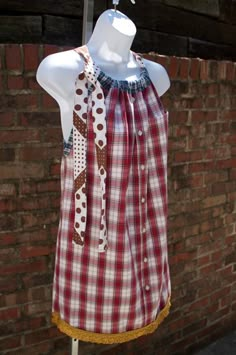 a white mannequin wearing a red and white checkered dress with ties on it