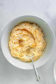 a white bowl filled with food next to a spoon