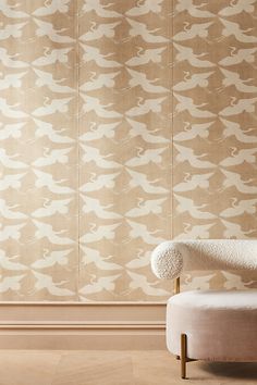 an upholstered chair in front of a wallpapered background with birds on it