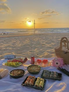 a picnic on the beach with food and drinks in front of the ocean at sunset