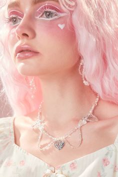 a woman with pink hair and white makeup is wearing a necklace, earrings and pearls