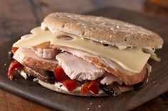 a sandwich with meat, cheese and vegetables on a cutting board