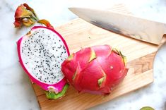 a dragon fruit cut in half on a cutting board with a knife next to it