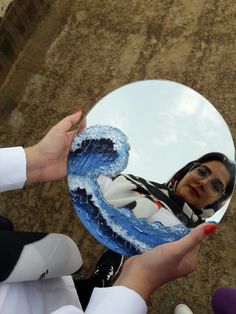 a woman holding up a mirror with her reflection in it