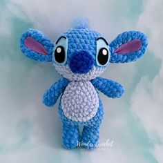 a blue crocheted stitched stuffed animal with big eyes and ears, standing on a white background