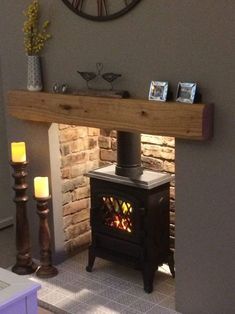 a wood burning stove in a living room next to two candles and pictures on the wall