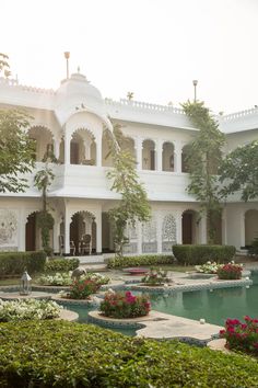 a large white building with lots of plants and flowers around it