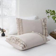 a bed with white sheets and pillows on top of it next to a vase filled with flowers