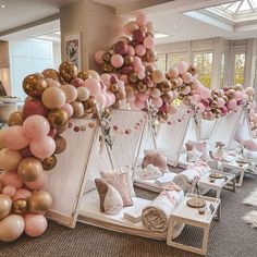 a room filled with lots of pink and gold balloons