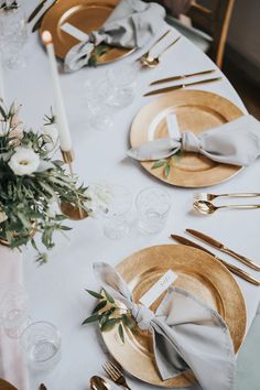 the table is set with gold plates and silverware